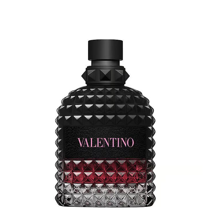 Valentino Uomo Born in Roma Intense Eau de Parfum – en glasflaska med rundade axlar täckt av Valentinos ikoniska nitar. Flaskan har en mörk toning från helt svart upptill till djuprosa nedtill, med en svart läderetikett och rosa logotyp, stående mot en vit bakgrund