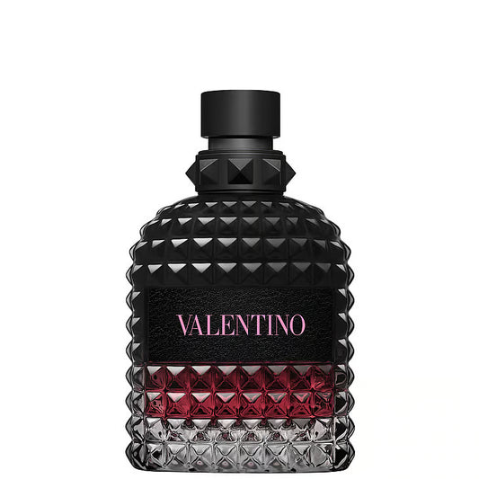 Valentino Uomo Born in Roma Intense Eau de Parfum – en glasflaska med rundade axlar täckt av Valentinos ikoniska nitar. Flaskan har en mörk toning från helt svart upptill till djuprosa nedtill, med en svart läderetikett och rosa logotyp, stående mot en vit bakgrund